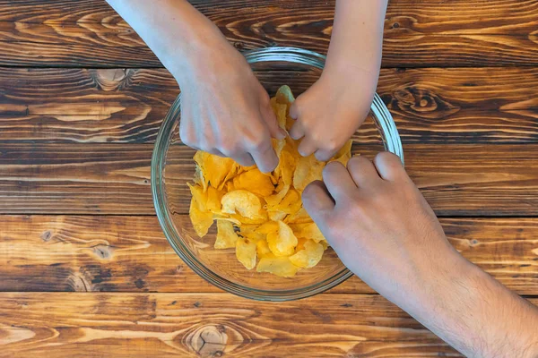 Family eating crisps from glass bowl, top view photo — Stock Photo, Image