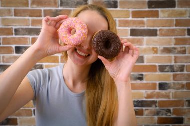 Neşeli ve gülümseyen kadın eğleniyor çörek ile poz