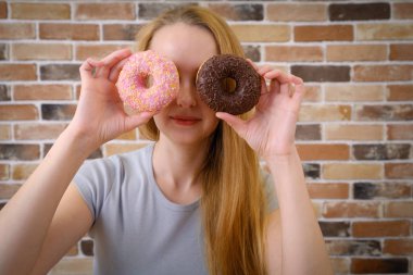 Neşeli ve gülümseyen kadın eğleniyor çörek ile poz
