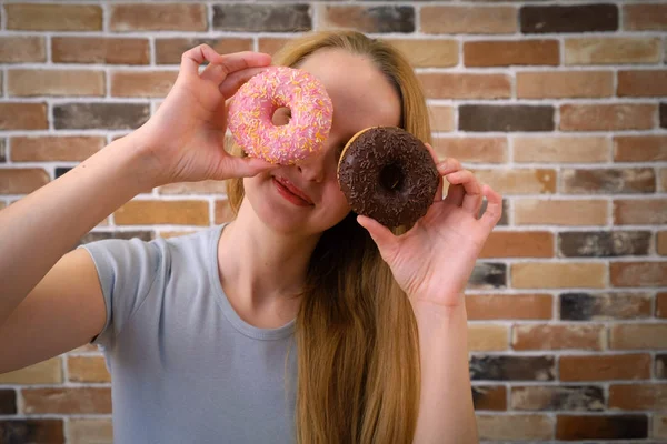 Улыбающаяся и радостная женщина, развлекающаяся позируя с пончиками — стоковое фото