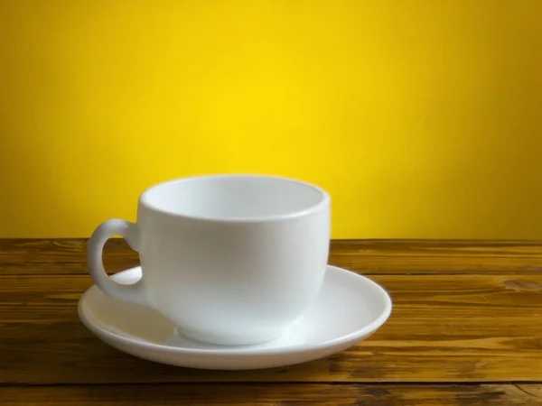 La taza de café blanco y el plato se quedan en la mesa de madera — Foto de Stock
