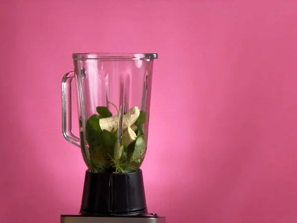 Gesunde grüne Smoothie-Mischung mit einem Mixer auf rosa Hintergrund — Stockfoto