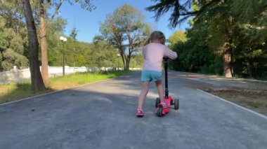 Park yerinde scooterlı genç bir kadın.