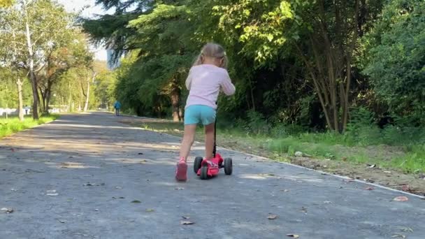 Niño feliz, linda chica aprendiendo a montar y el equilibrio en la vespa de empuje . — Vídeos de Stock