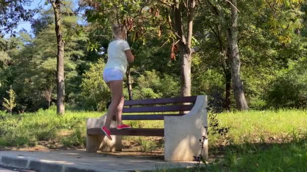 Jovem atraente mulher magra fazer ginástica no parque . — Vídeo de Stock