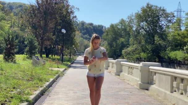 Donna sportiva che corre nel parco della città indossando Smartwatch — Video Stock