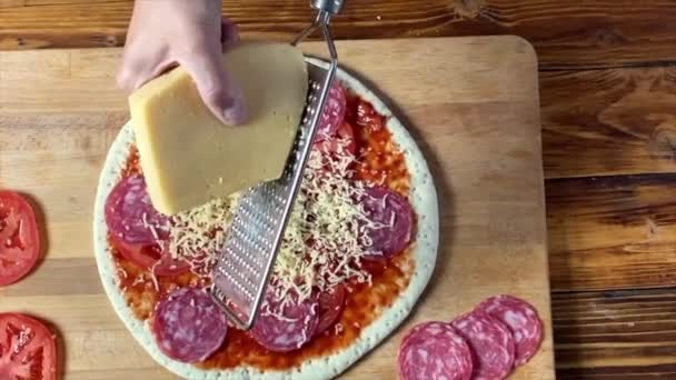 Woman is grating cheese for Pepperoni pizza — Stock Video