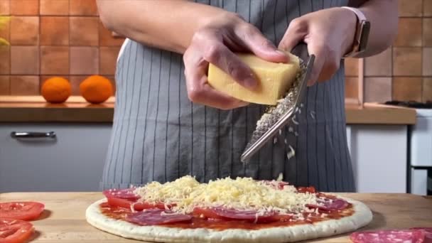Vrouw raspt kaas voor Pepperoni pizza — Stockvideo