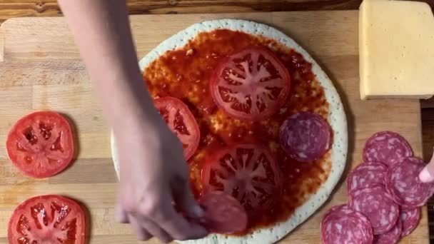 Cuisiner une pizza. Main femme cuisinier met tranche de salami sur la pâte . — Video