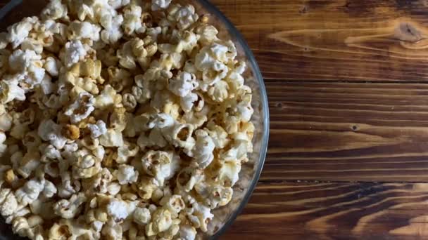 Popcorn w szklanej misce na drewnianym tle — Wideo stockowe