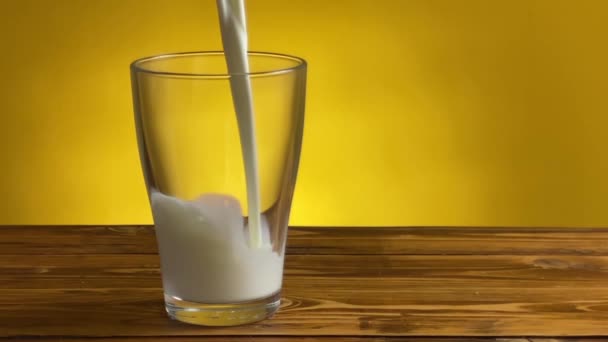 Выливание молока из кувшина в стекло на деревенский деревянный стол — стоковое видео