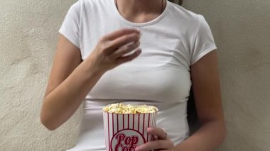 TV ekranına bakarken patlamış mısır yiyen kadın