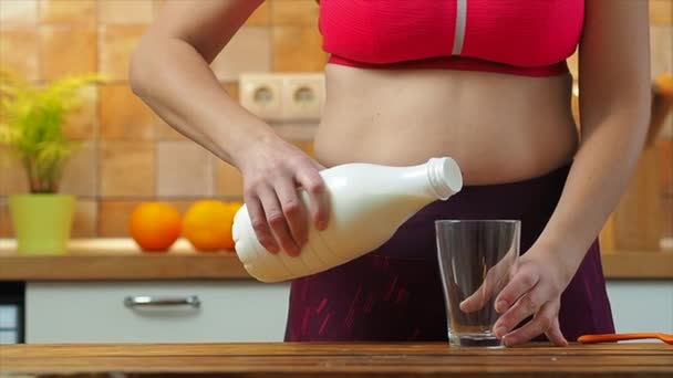 Sportig flicka häller mandelmjölk i ett glas i köket, slow motion — Stockvideo