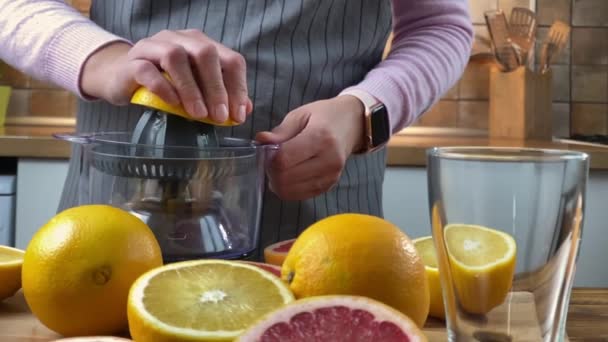 電気ジューサーで柑橘系ジュースを絞るキッチンの女性. — ストック動画