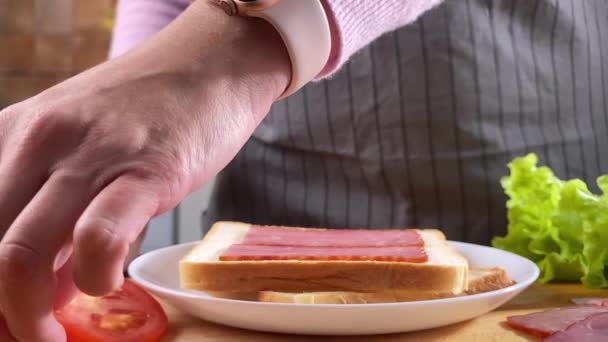 Mulher cozinhar sanduíche na cozinha com salada, bacon e tomate — Vídeo de Stock