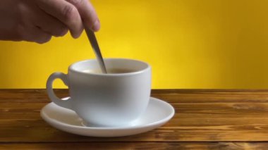 Kadınların eli kapuçinoyu beyaz bardakta şekerle karıştırıyor.