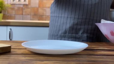 Patates kızartmasını tabağa koyan bir kadının elleri, ağır çekim.