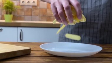 Patates kızartmasını tabağa koyan bir kadının elleri, ağır çekim.