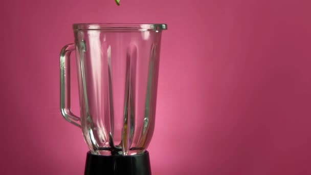 Spinazie valt naar beneden naar blender op roze achtergrond — Stockvideo