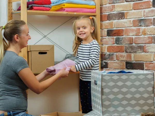 Mamá y su hijita ponen ropa diferente en cajas — Foto de Stock