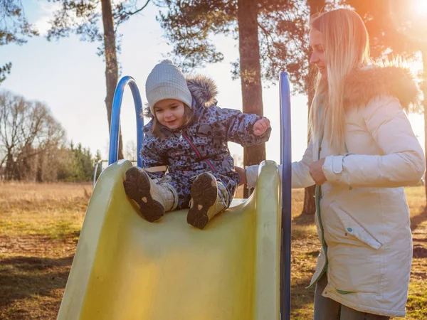 Girl riding on a swing in the winter time at playground, slow motion — Stock Photo, Image