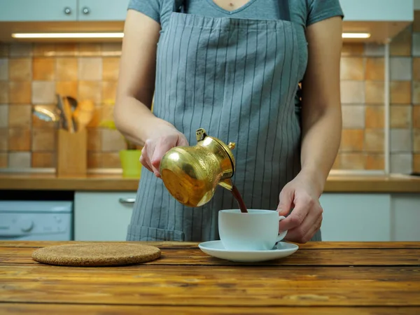 Woman pouring black coffee from turkish traditional coffee pot — Stock Photo, Image