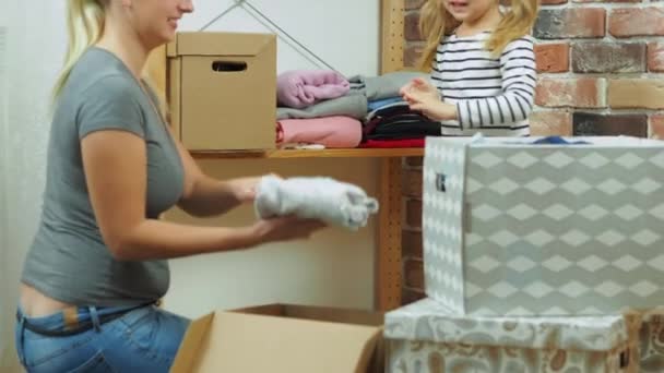 Mam en dochtertje doen verschillende kleren in dozen. — Stockvideo
