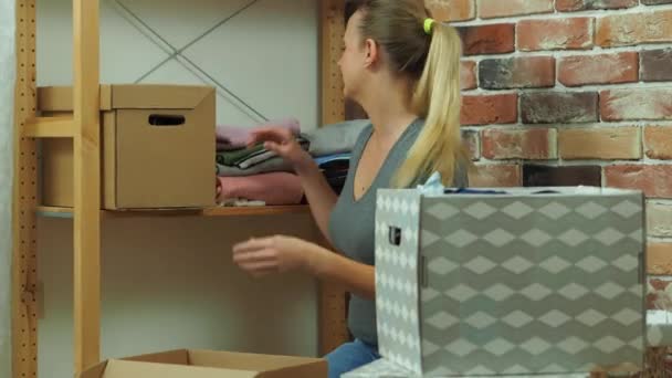 Dívka dává oblečení z police v lepenkové krabici — Stock video