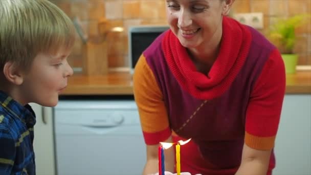 子供たちはお母さんを保つ誕生日ケーキにろうそくを吹き消す — ストック動画