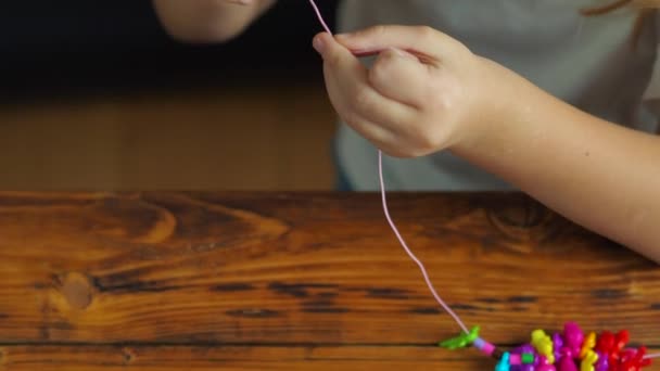 Cute little baby girl make a bracelet from beads — ストック動画