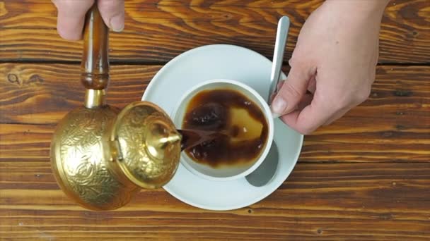 Женщина наливает черный кофе из турецкого традиционного кофейника — стоковое видео