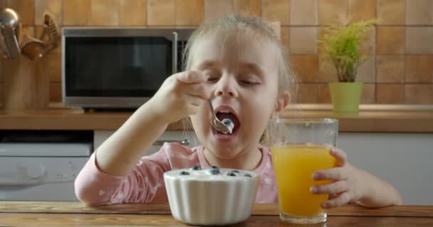 Девочка ест здоровый йогурт с черникой — стоковое видео