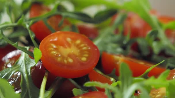 Оливковое масло на салат с помидорами черри и рукколой, замедленная съемка — стоковое видео