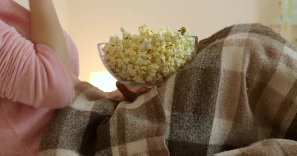 Vrouw kijkt film ligt in bed en eet popcorn — Stockvideo