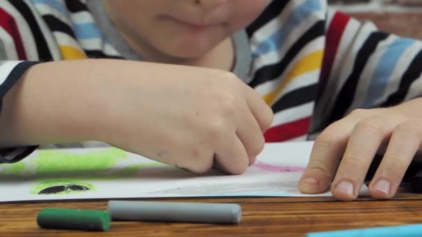 Маленький мальчик рисует воском на бумаге, крупным планом — стоковое видео