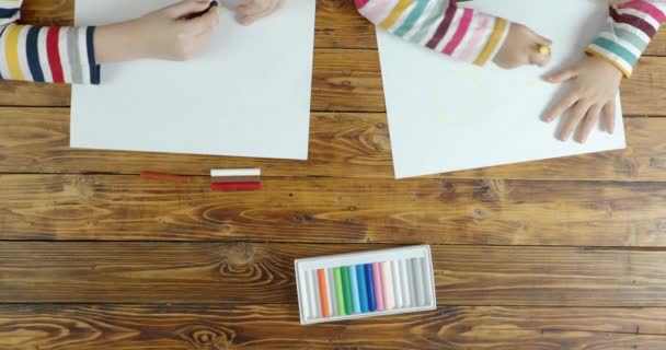 Jongen en klein meisje tekening door pastel op papier, bovenaanzicht — Stockvideo