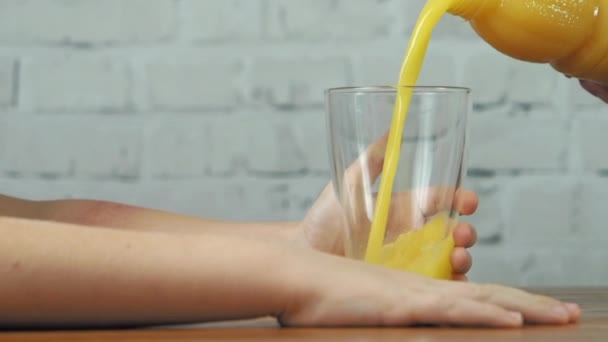 Mère versant le jus d'orange au verre dans les mains du garçon, au ralenti — Video