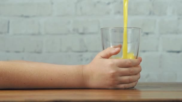 Moeder gieten sinaasappelsap naar glas in de handen van de jongen, slow motion — Stockvideo