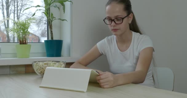 Genç kız tablette seriye bakıyor ve patlamış mısır yiyor. — Stok video