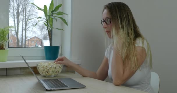 Mujer joven comiendo palomitas de maíz y viendo películas en el portátil — Vídeos de Stock