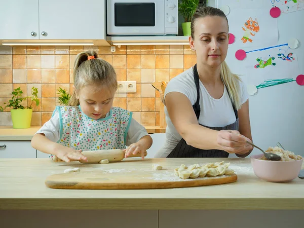 Joven madre con su pequeña hija cocinando en la cocina — Foto de Stock