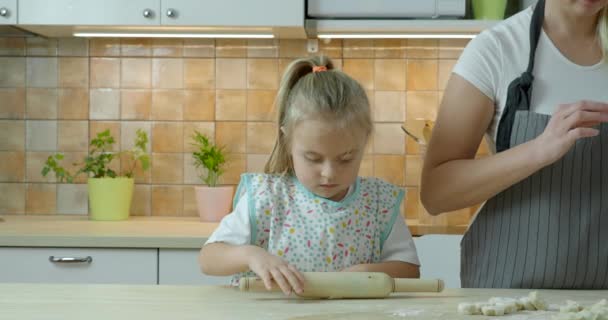 Küçük kızı olan genç bir anne mutfakta yemek pişiriyor. — Stok video