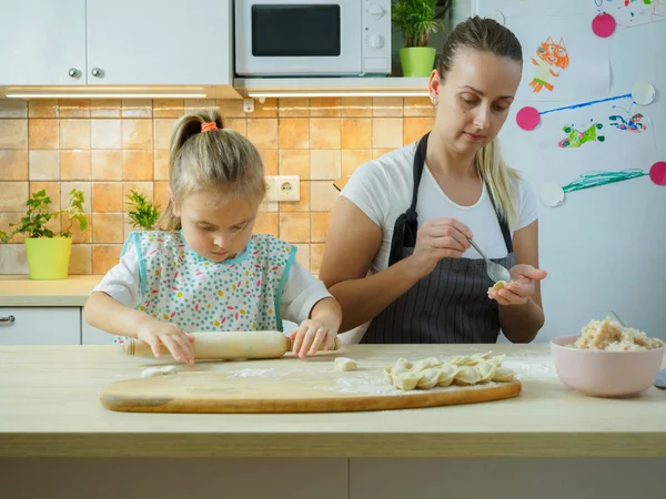 Joven madre con su pequeña hija cocinando en la cocina — Foto de Stock