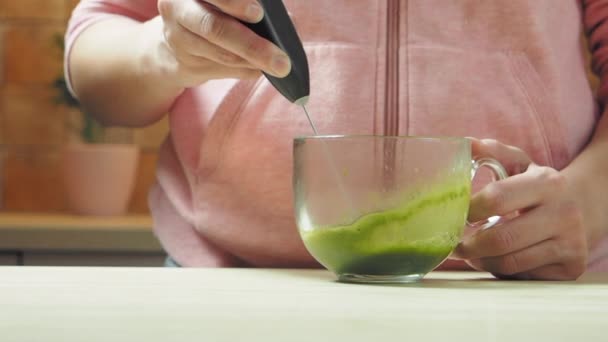 Kvinna gör matcha te, blandat vatten med matcha pulver, slow motion — Stockvideo