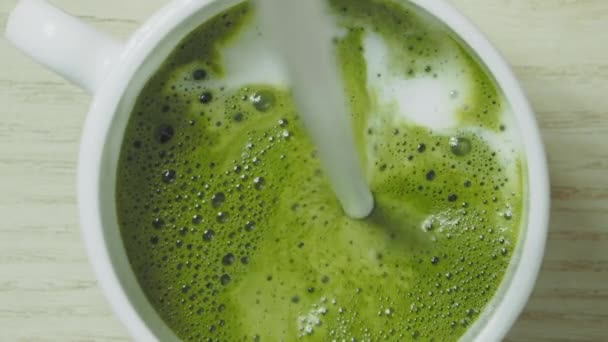 Verter leche en té matcha verde, cámara lenta — Vídeos de Stock