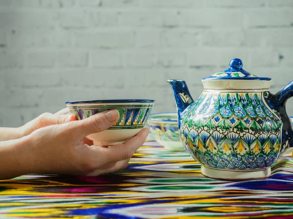 Touristenhände und traditionelle usbekische Teekanne — Stockfoto
