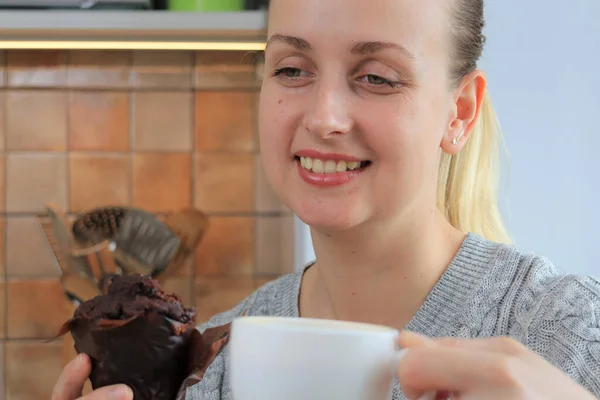 Face of woman eating muffins with coffee on the kitchen, close-up view — Stock Photo, Image