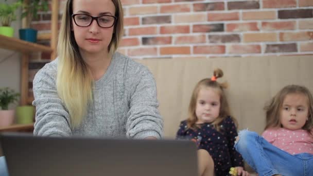 Dos niñas jugando cerca de la madre y no permitiéndole trabajar en casa — Vídeo de stock