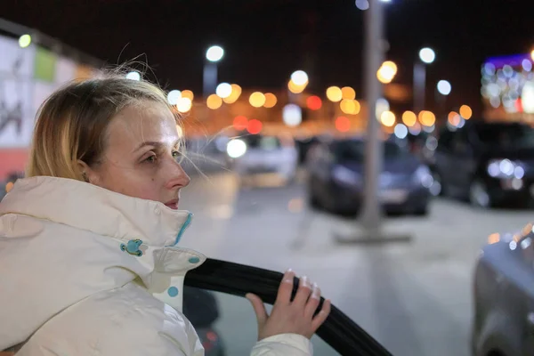 Молодая девушка выходит из машины на парковке вечером — стоковое фото
