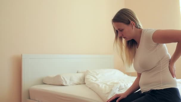 Young plump woman sitting in bedroom with backache — Stock Video